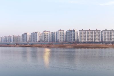 Sea by cityscape against clear sky