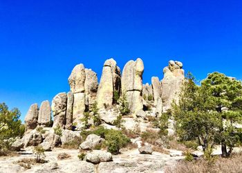 Low angle view of rock formation against clear blue sky