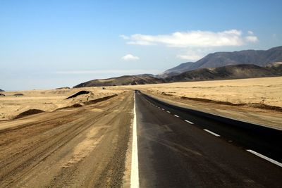 Road amidst desert against sky