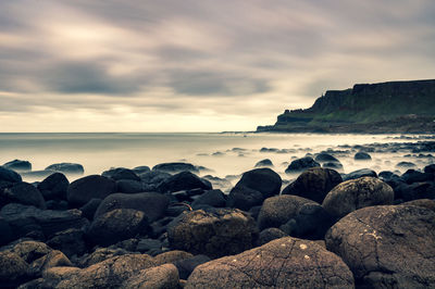 Rocks on beach against sky during sunset