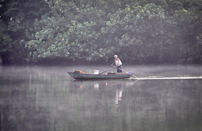 Man in boat on lake against trees