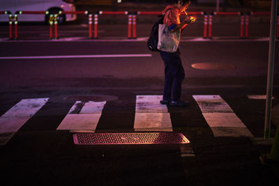 Rear view of man standing on road at night