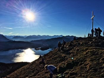 Silhouette people on mountains against sky during sunny day