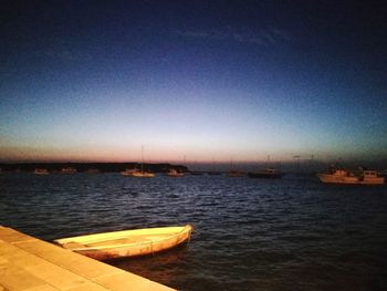 Boats sailing in sea against clear sky at night
