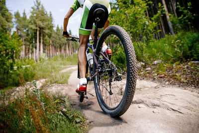 Low section of man riding bicycle on field