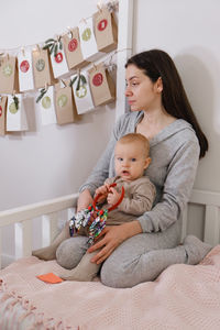 Mother with infant child having fun christmas advent calendar tasks and gifts. baby boy excited