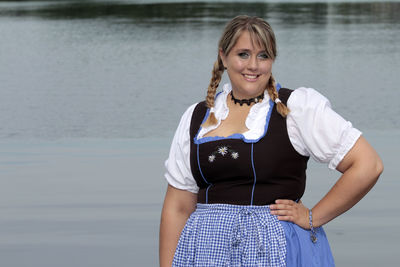 Portrait of happy woman wearing dirndl against lake