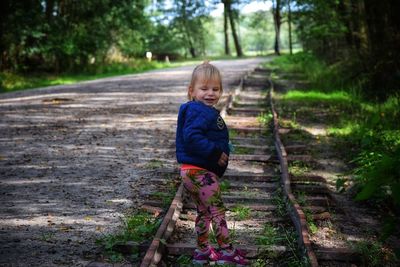 Side view of cute baby girl standing on railroad track