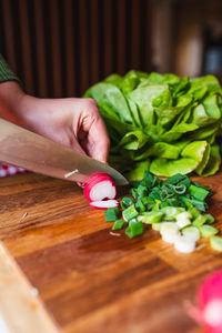 Cropped hand of woman with vegetables on cutting board