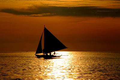 Silhouette sailboat sailing on sea against sky during sunset