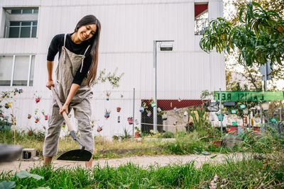 Happy young woman gardening with shovel in urban garden