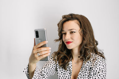 Portrait of young woman using smart phone against white background