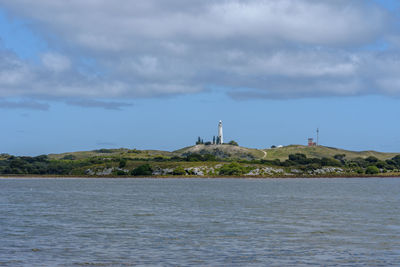 Lighthouse by sea against sky