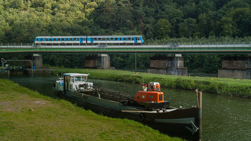 Boat at canal with train moving on railway bridge