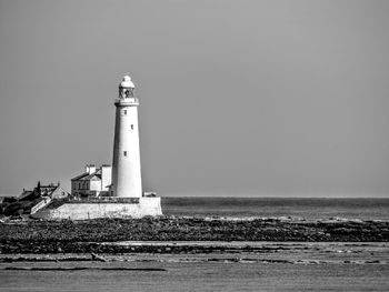 Lighthouse by sea against sky