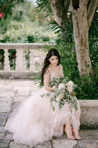 Full length of woman sitting on stone wall