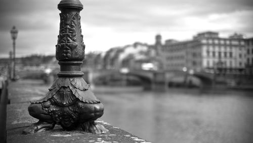 Close-up of old bridge over river against buildings