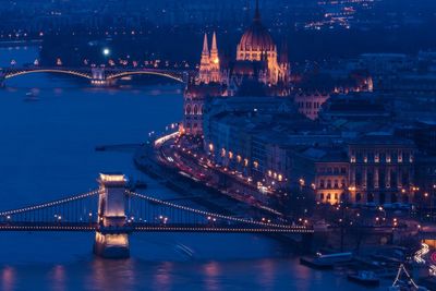 Illuminated bridge over river in city at night