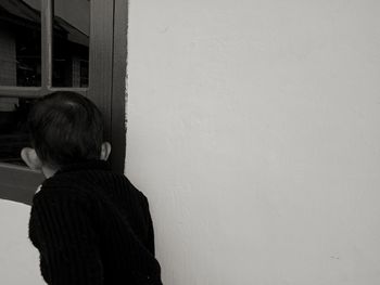 Rear view of woman standing against wall