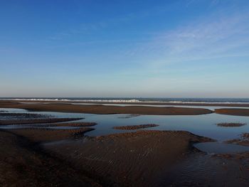 Scenic view of beach against blue sky