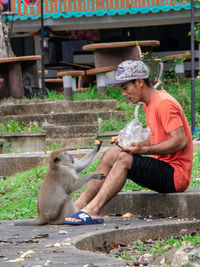 Full length of young man sitting outdoors