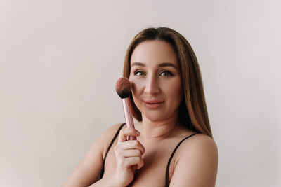 A beautiful natural woman makeup artist preens herself with makeup on a white isolated background