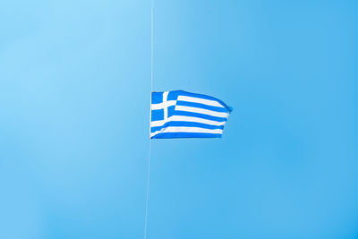 Low angle view of flag against clear blue sky