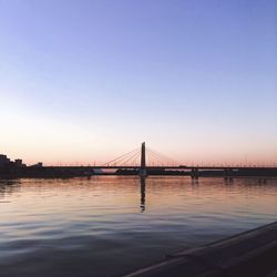 Bridge over river against sky during sunset