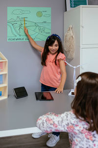 Student showing types of renewable energies in poster at ecology classroom