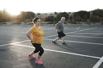 A middle-aged couple are exercising in a car park