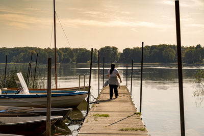 Rear view of man standing on boat moored at lake