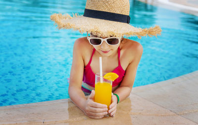 Girl drinking orange juice by pool