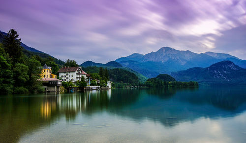 Scenic view of lake and mountains against cloudy sky during sunset