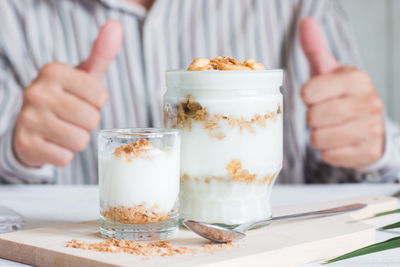 Midsection of person holding ice cream in glass on table