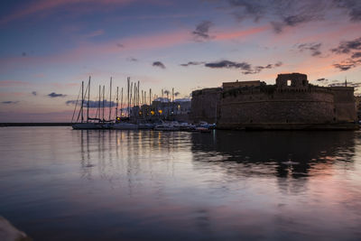 Angevin castle by harbor against sky during sunset