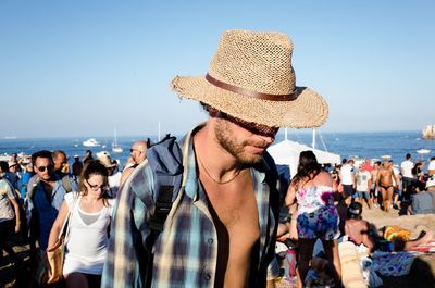 People standing at beach against clear sky