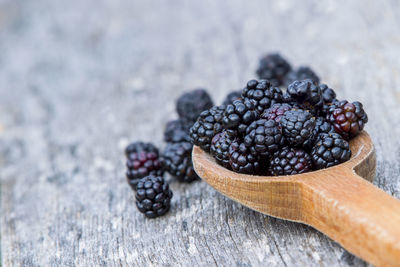 High angle view of blackberries with wooden spoon on table