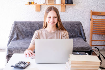 Young woman using phone while sitting on table