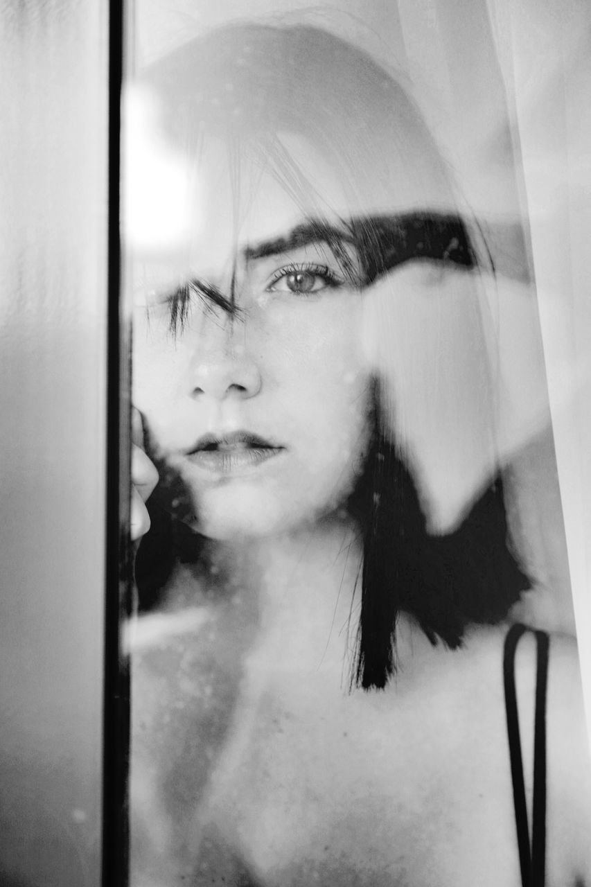 PORTRAIT OF WOMAN IN GLASS WINDOW