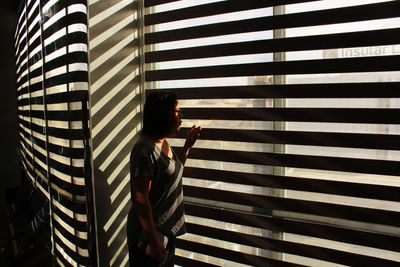 Side view of man standing against window