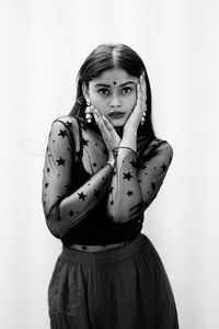 Portrait of young woman standing against gray background