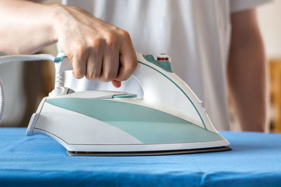 Midsection of man ironing garment on board