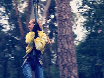 Full length of young woman in tree trunk in forest