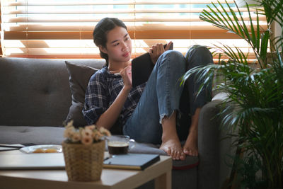 Young woman using digital tablet while sitting on sofa