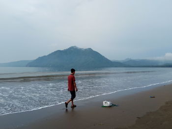 Rear view of man on beach against sky