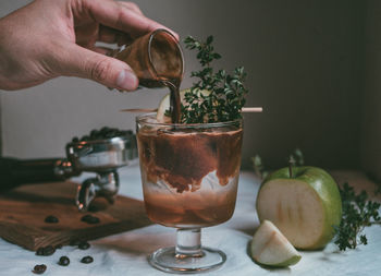 Cropped hand pouring drink in glass on table