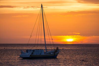 Sailboat on sea against romantic sky at sunset