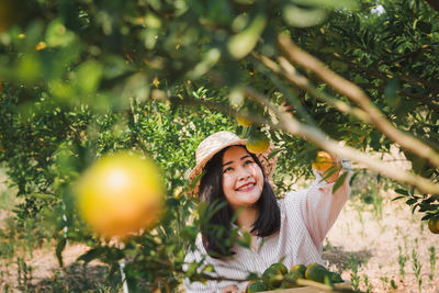 Smiling woman harvesting citrus fruit at farm