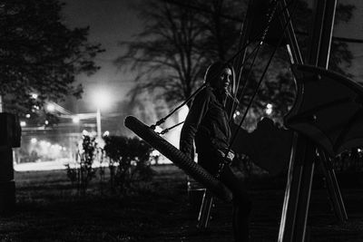 Young woman swinging at playground during night