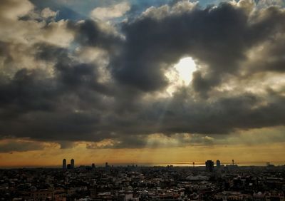 View of city against cloudy sky during sunset